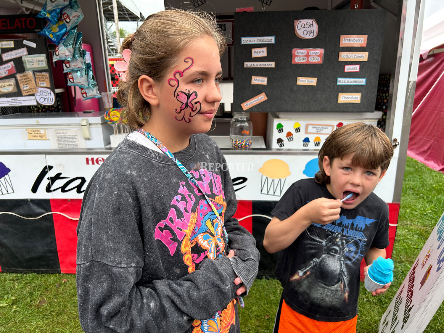 Eleanor White shows off her face paint, done by artists in the art exhibit building, while her brother Peter enjoys an Italian ice on Tuesday, Aug. 15.